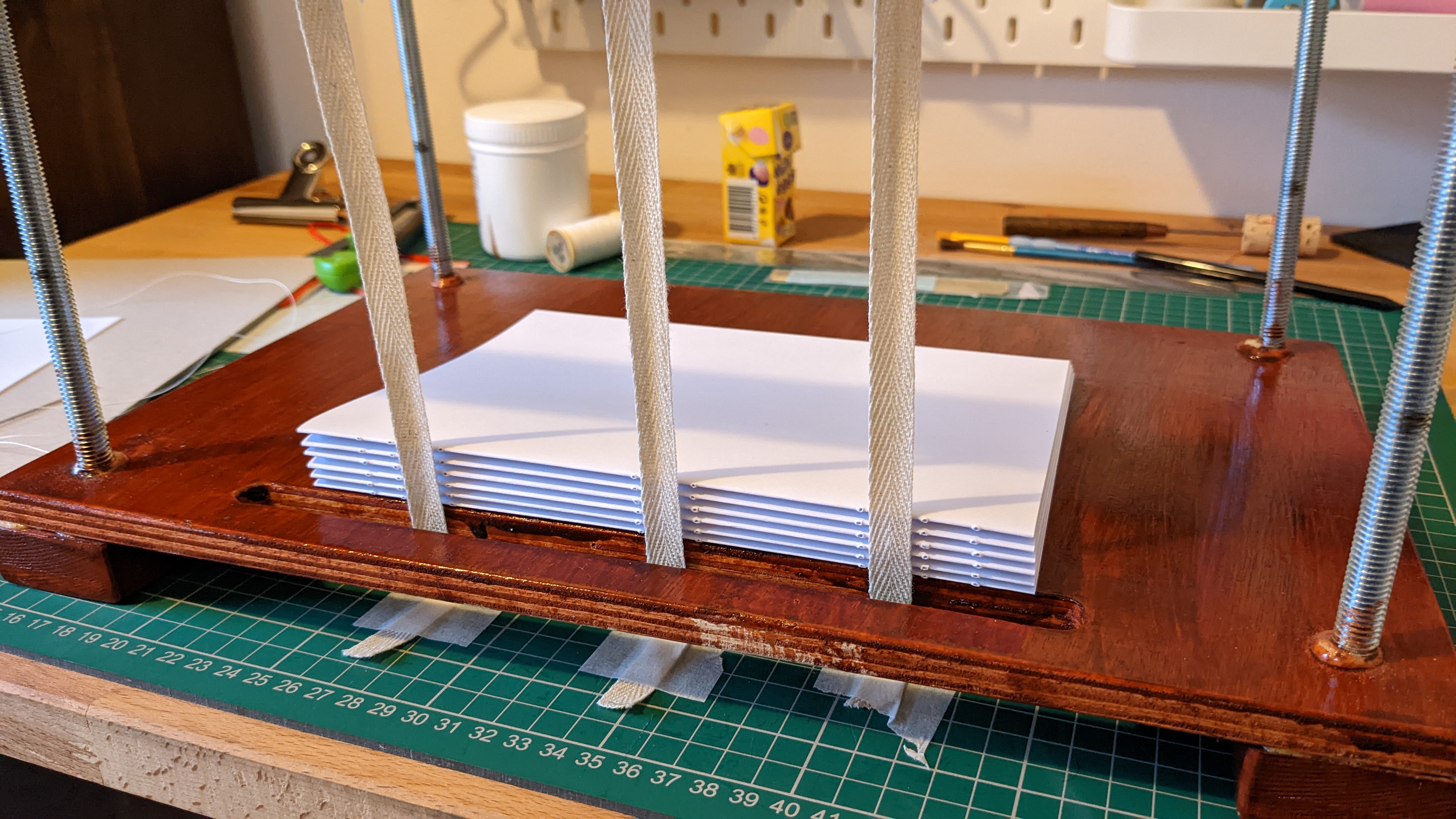 Notebook signatures on book press/sewing frame, waiting to be sewn onto tapes